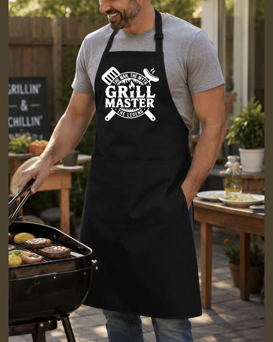 Black Grill Master BBQ apron with crossed utensils graphic worn by man grilling burgers outdoors