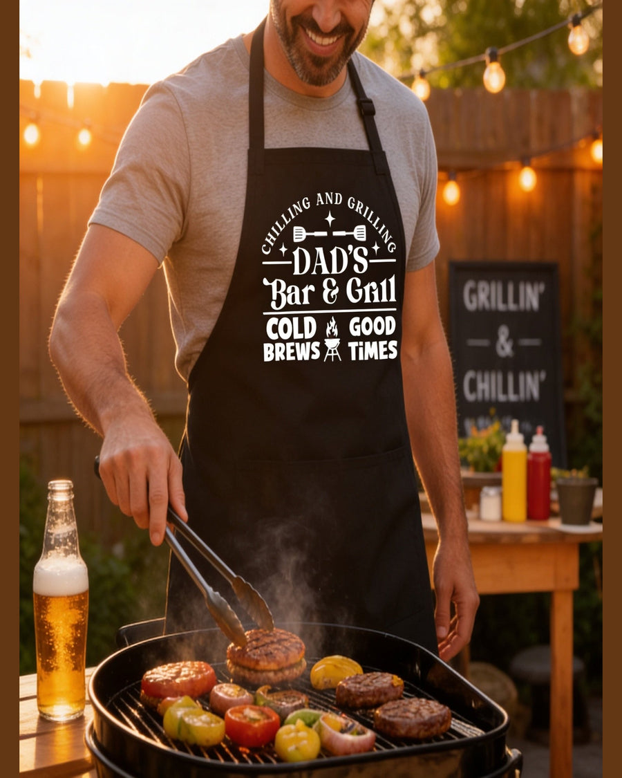 Close-up of black Dad's Bar & Grill apron featuring Cold Brews Good Times text on smiling dad grilling