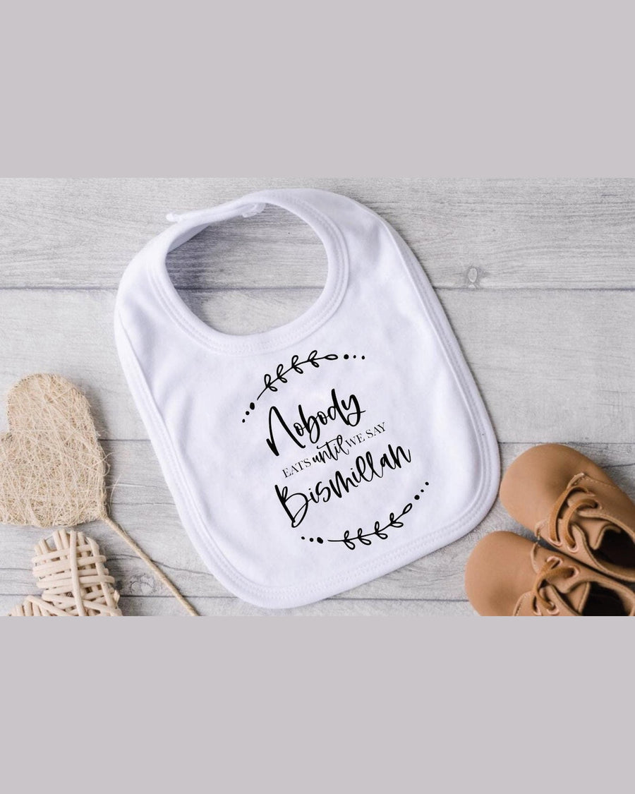 White Bismillah baby bib with Nobody EATS until WE SAY printed text and leafy vine motifs