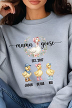 A gray sweatshirt with a graphic design featuring three cartoon ducks and the text "mama goose" above them.