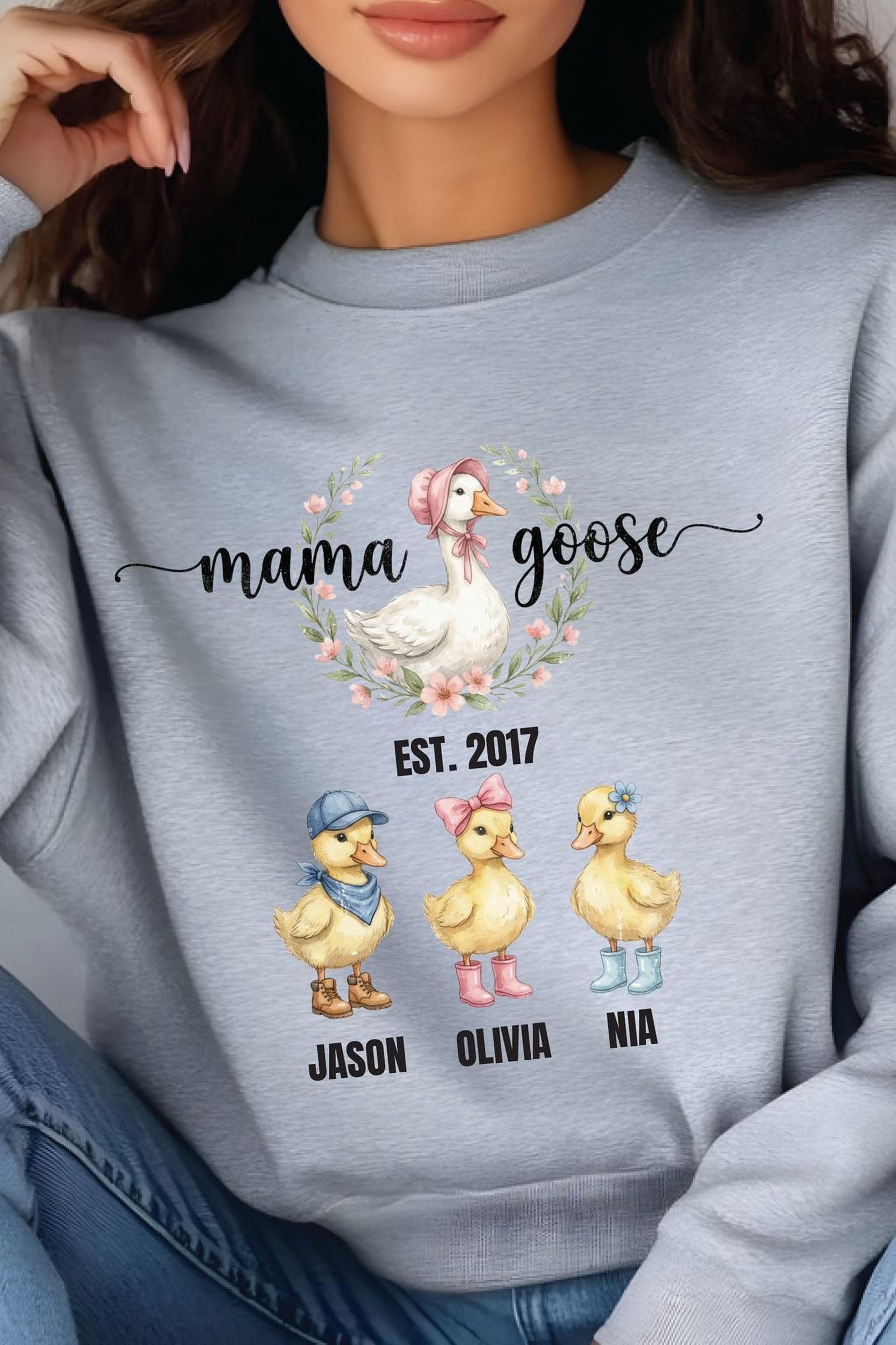 A gray sweatshirt with a graphic design featuring three cartoon ducks and the text "mama goose" above them.