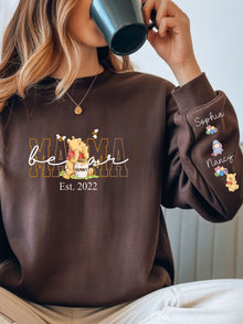 A woman wearing a brown sweatshirt with a Winnie the Pooh character printed on it, holding a mug to her face.