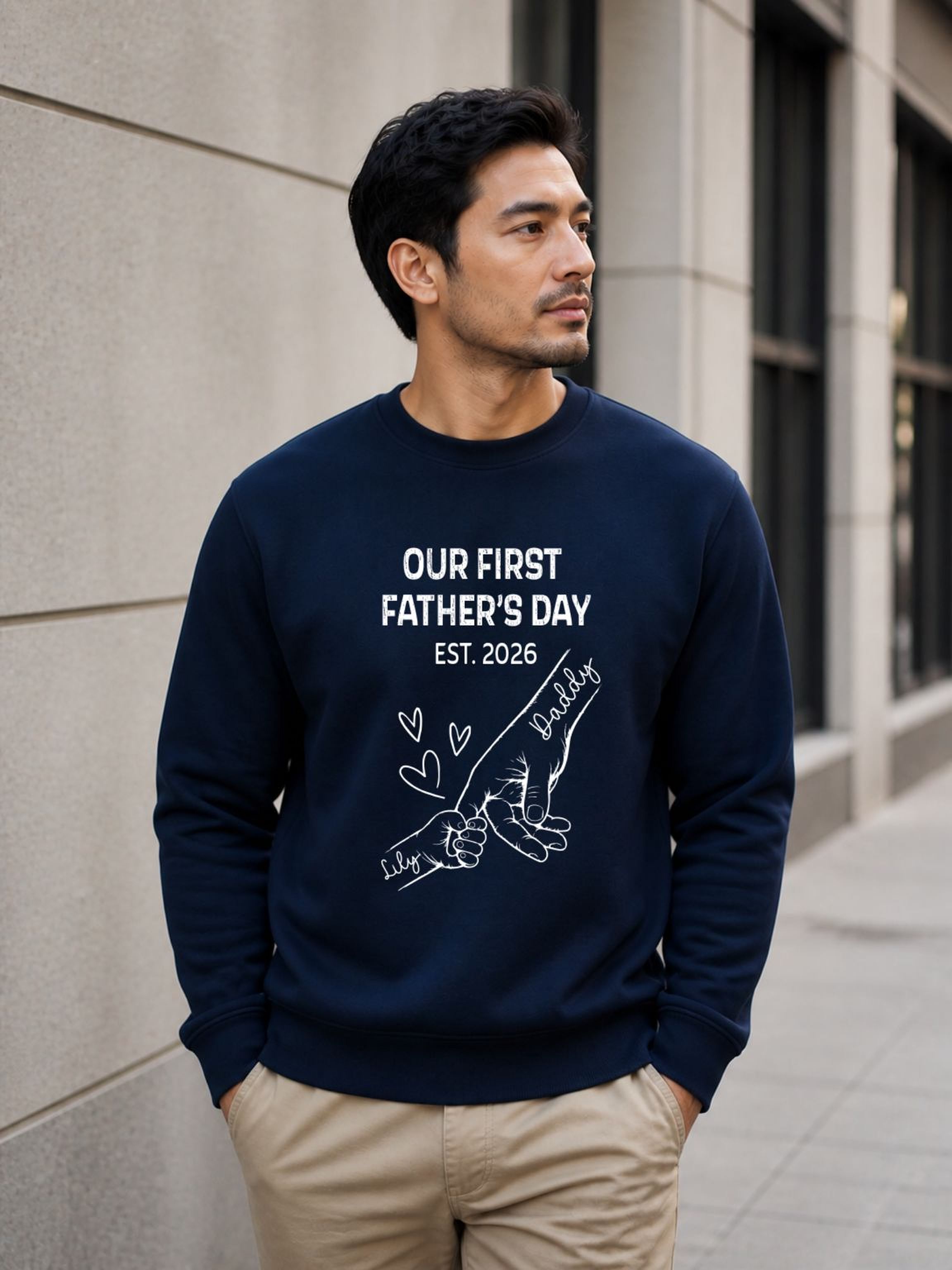 sweatshirt featuring personalized Our First Father’s Day design with minimalist daddy and baby hand outline artwork worn by male model outdoors.