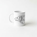 A white ceramic mug with a black and white illustration of two hands, one larger and one smaller, connected by a fist. The text "Daddy, Tyler, Liza, Nathan" is written above the illustration.