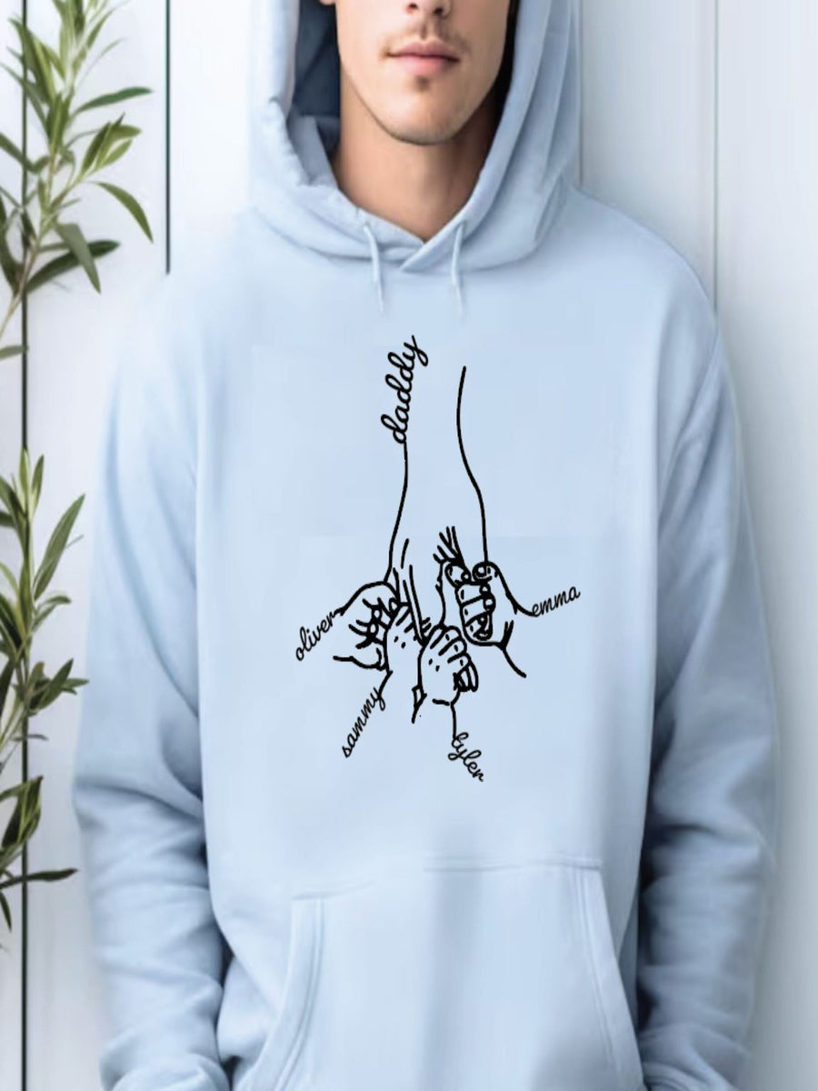 A person wearing a light blue hoodie with a black graphic design depicting a hand holding a family tree with the names of family members.