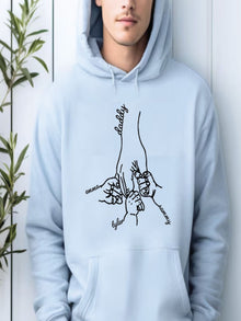 A person wearing a light blue hoodie with a graphic design depicting a hand holding a child's hand.