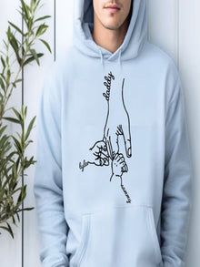 A person wearing a light blue hoodie with a hand drawing and the words "daddy" and " Tyler" printed on it.