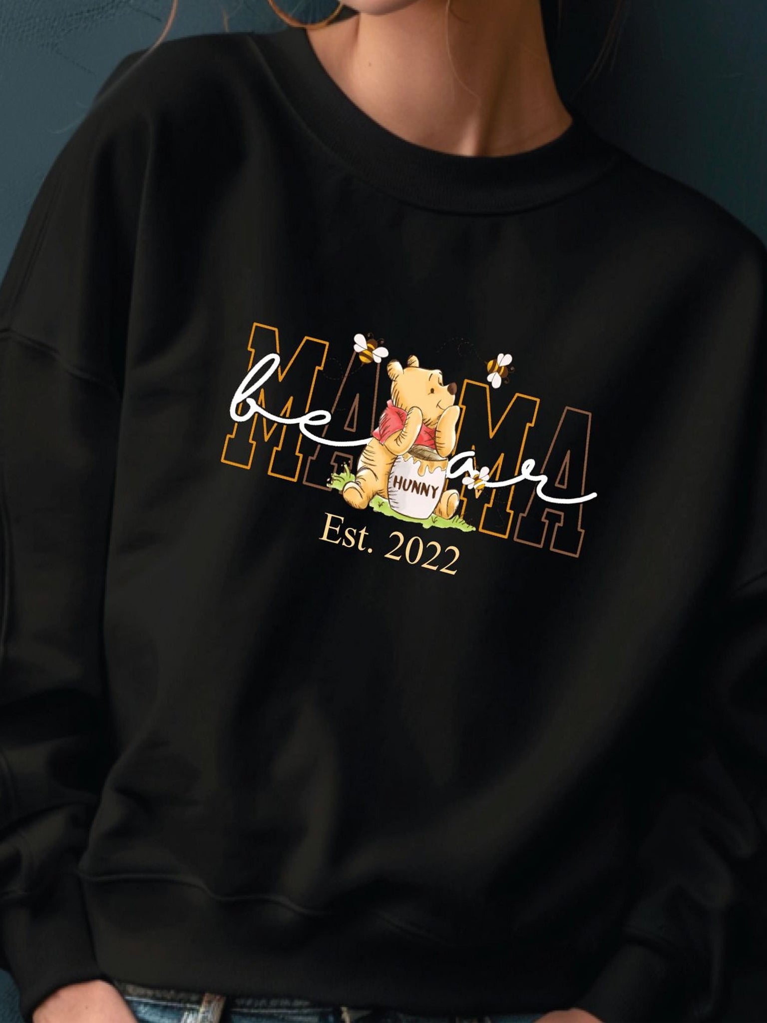 A black sweatshirt with a Winnie the Pooh logo and text printed on it.