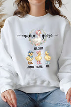 A white sweatshirt with a graphic design featuring three cartoon ducks and the text "mama goose" above them.