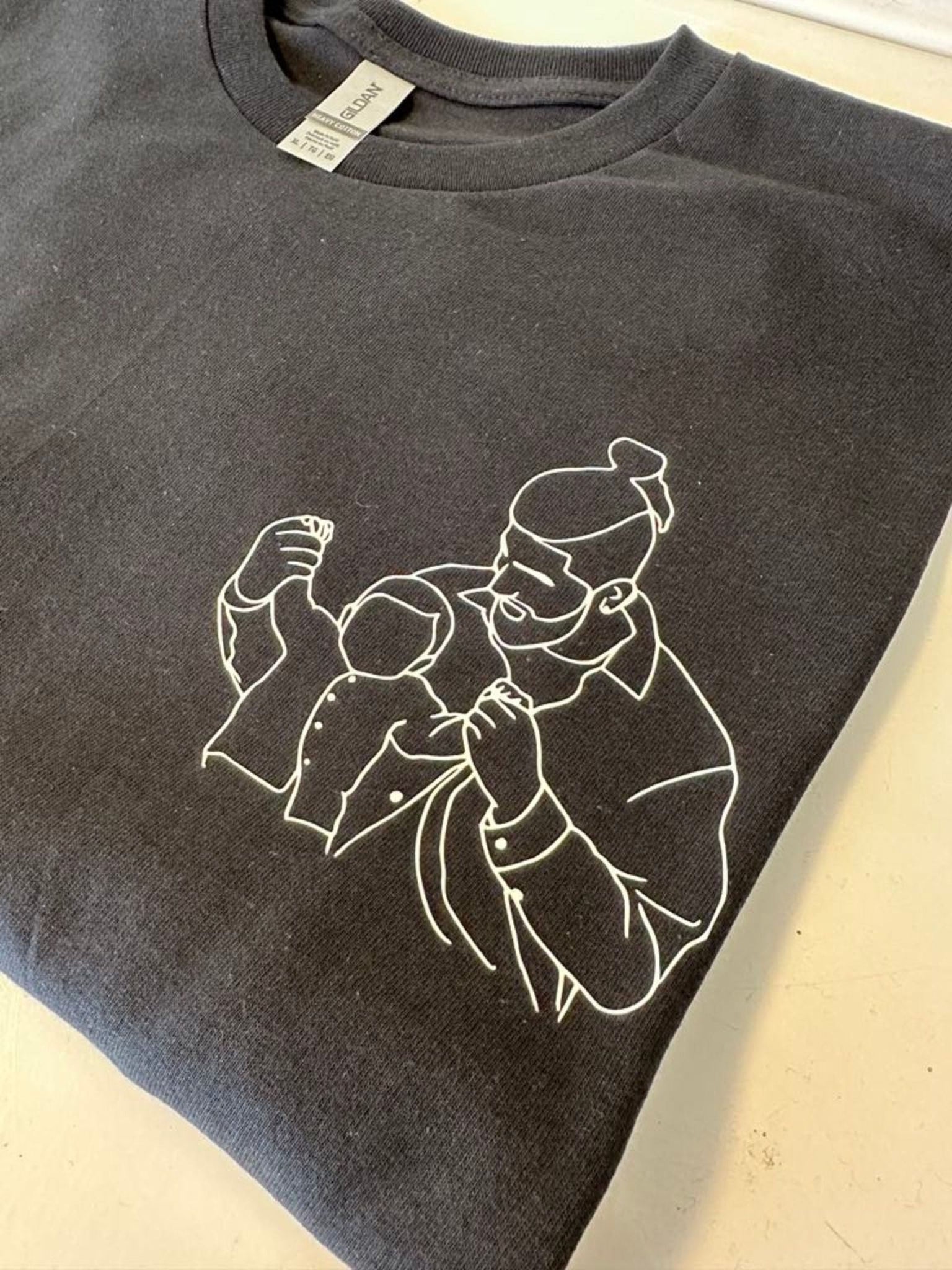 A gray t-shirt with a white line drawing of a person on it.