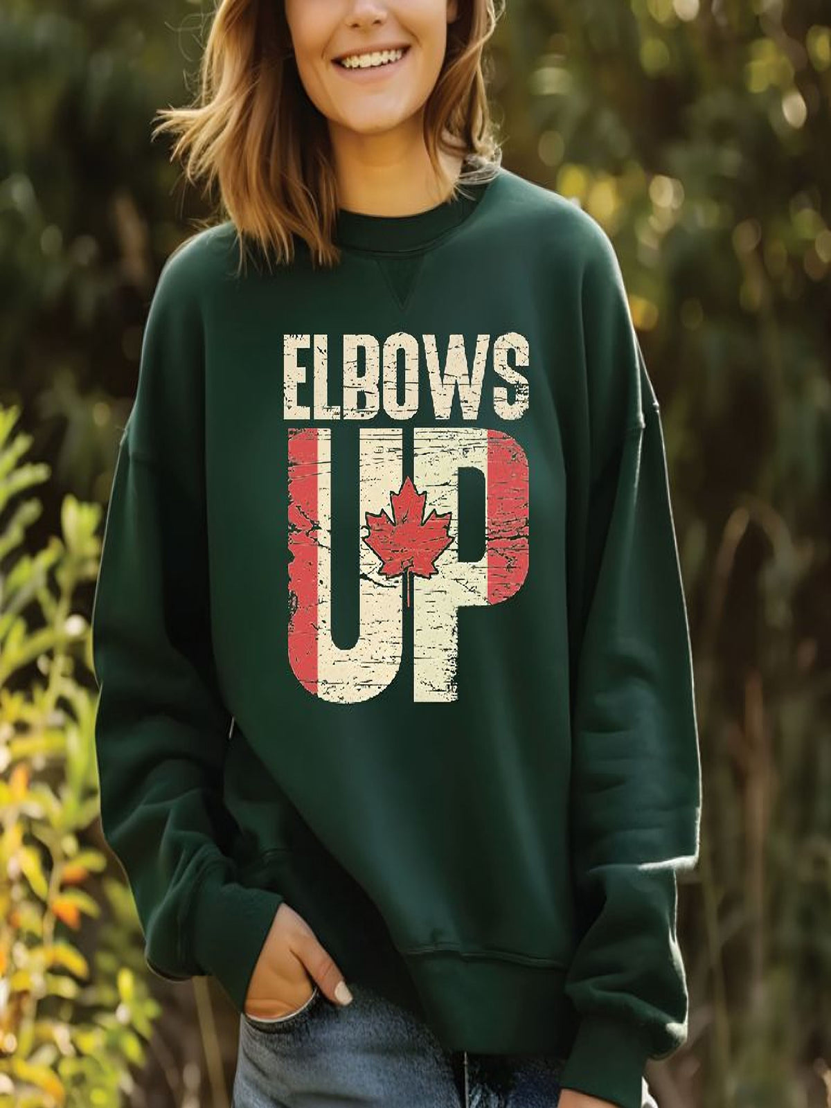 sweatshirt featuring an Elbows Up graphic with a distressed Canadian flag and red maple leaf design representing Canadian pride.
