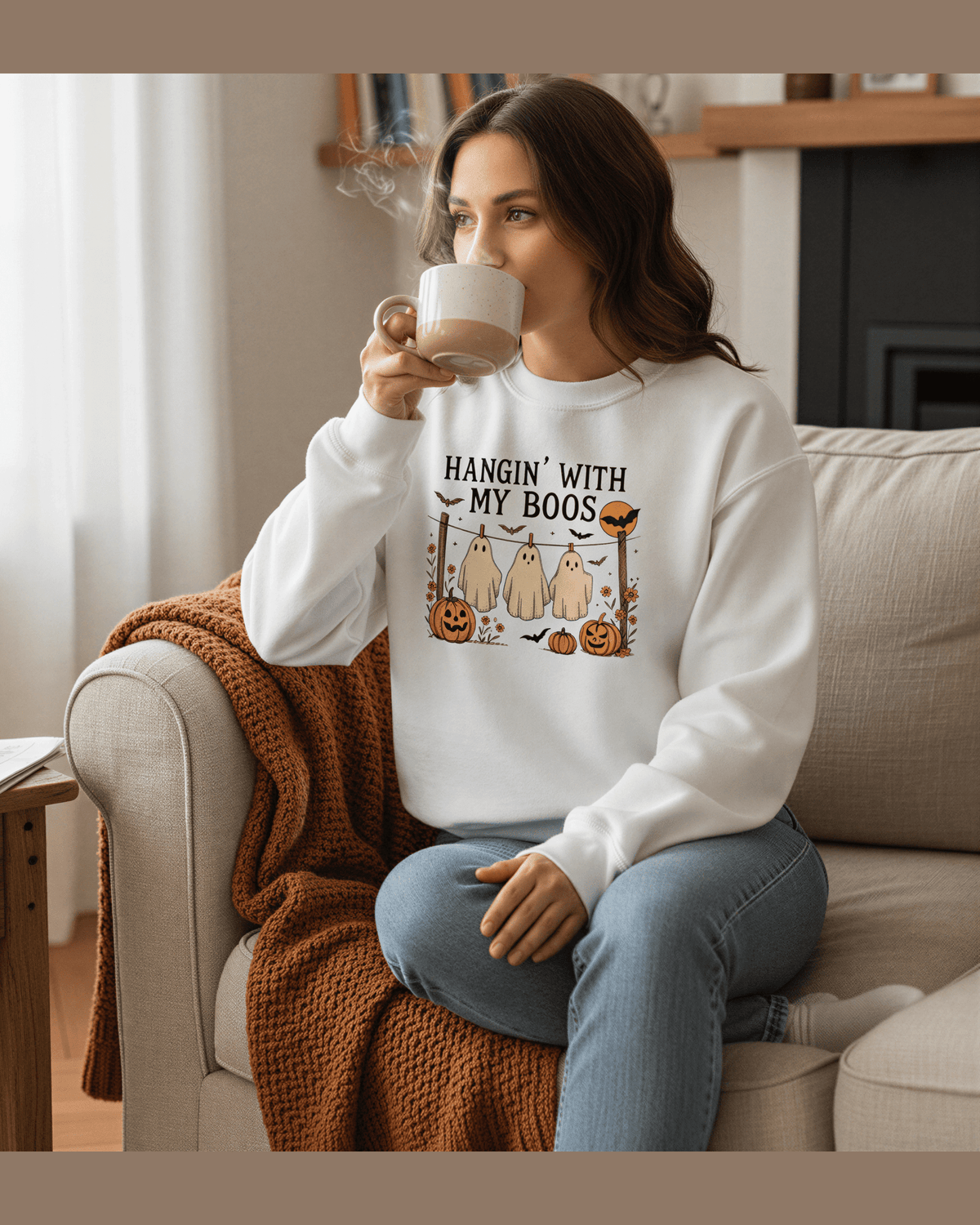 Woman wearing white Halloween sweatshirt with 'Hangin With My Boos' ghost graphic and pumpkins