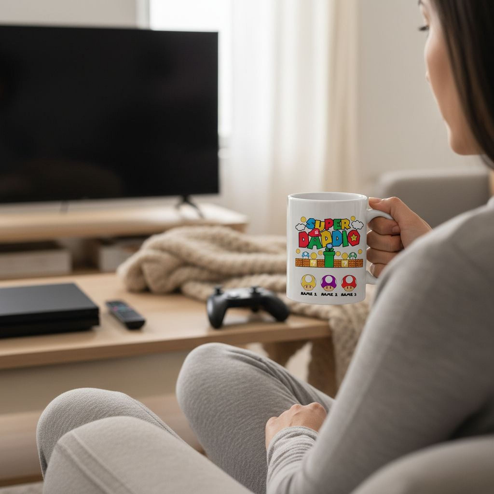 A person is sitting in a chair, holding a mug with a colorful design, while a flat-screen TV is visible in the background.