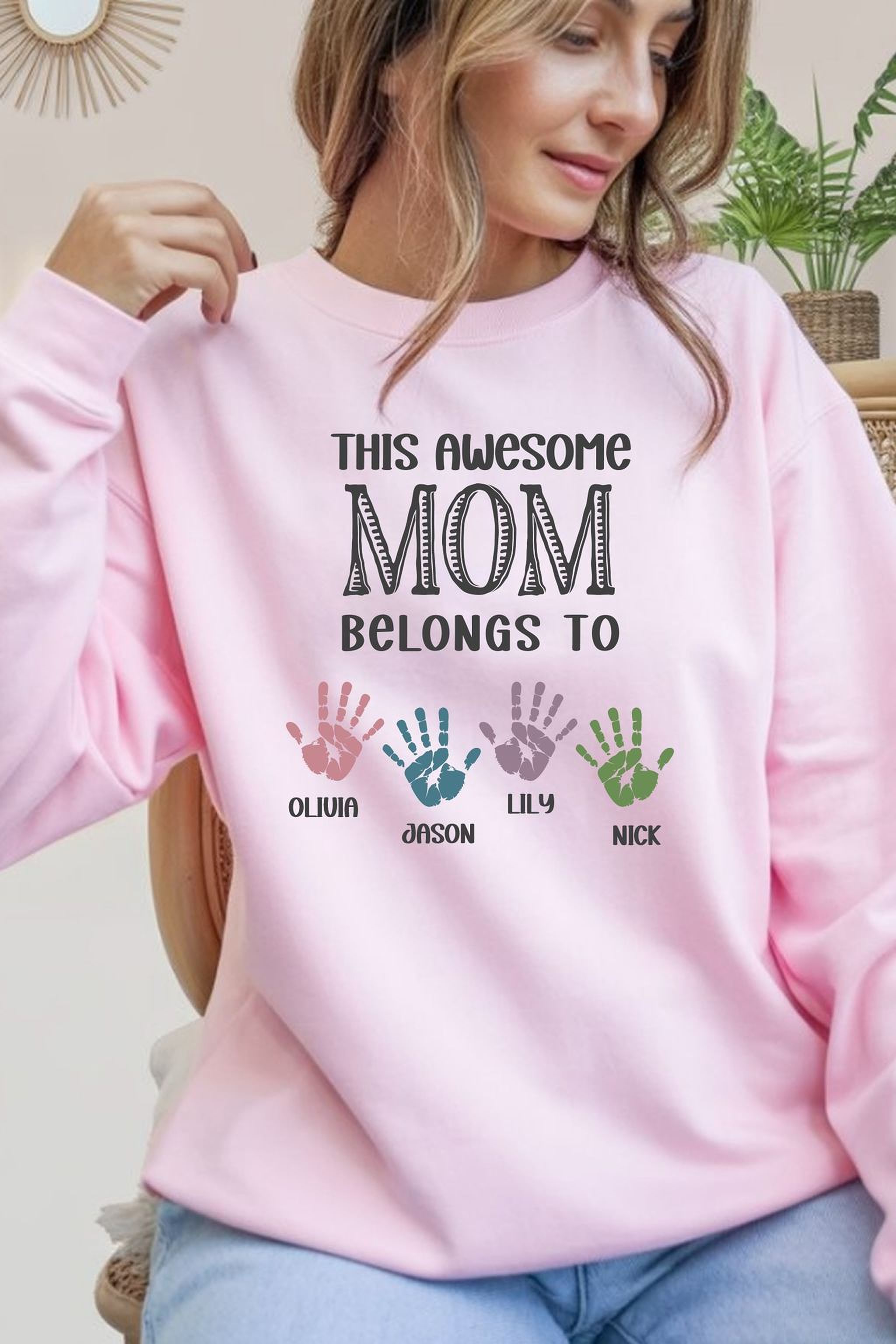 A woman wearing a pink sweatshirt with text and handprint designs.