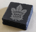 A set of four dark gray slate coasters featuring the logo of the Toronto Maple Leafs hockey team.