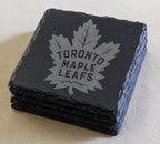 A set of four dark gray slate coasters featuring the logo of the Toronto Maple Leafs hockey team.