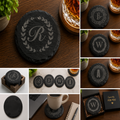 Personalized round black slate coaster engraved with custom monogram initial, elegant decorative border design, custom wedding and housewarming gift.