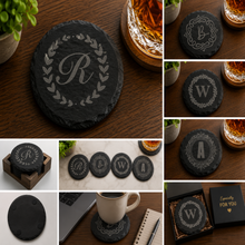 Personalized round black slate coaster engraved with custom monogram initial, elegant decorative border design, custom wedding and housewarming gift.