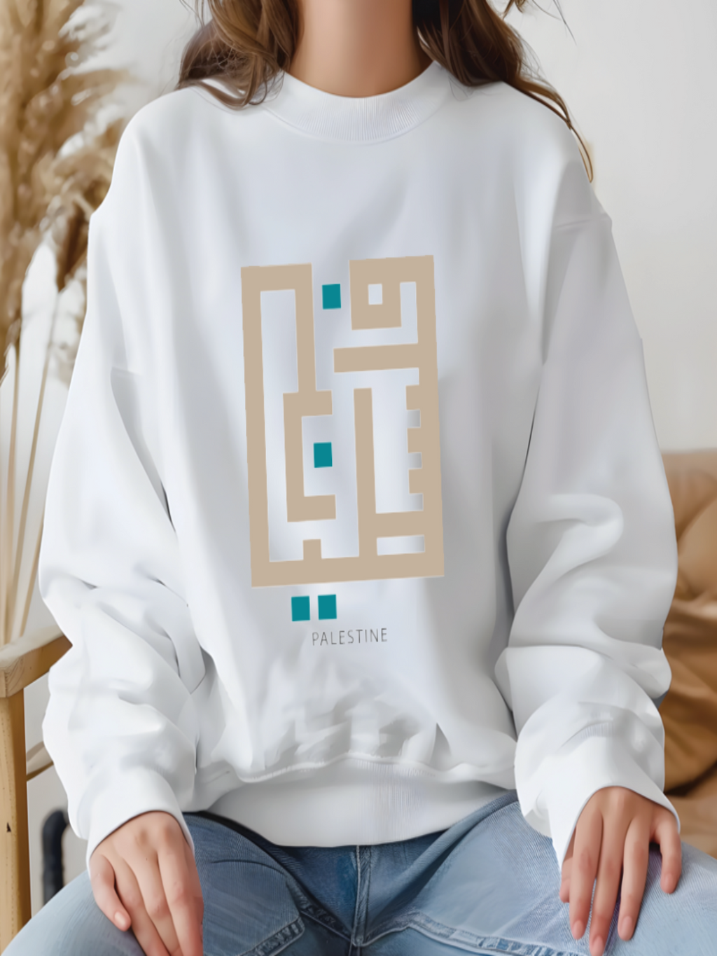 White sweatshirt with geometric design and 'Palestine' text worn by a person.