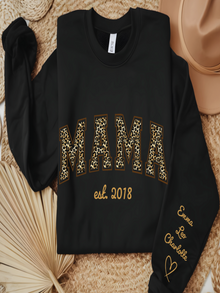 Black sweatshirt with 'MAMA est. 2018' text on a textured surface