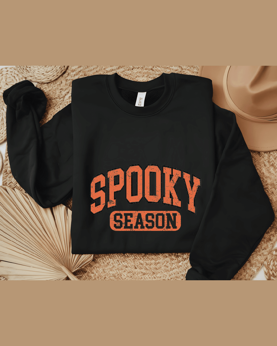 Black custom name sweatshirt flat lay showing Spooky Season DTF print and care tag
