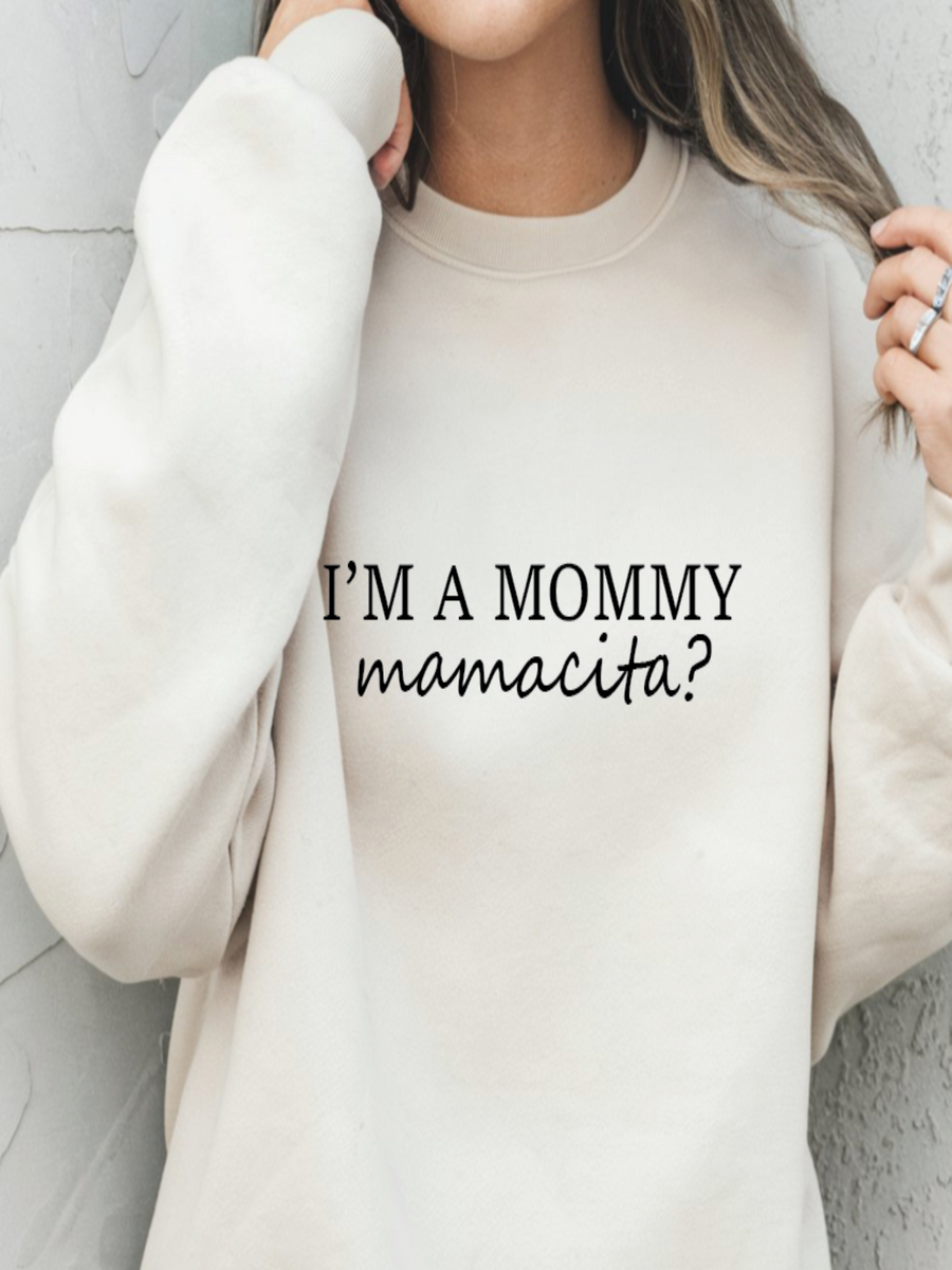 Person wearing a white sweatshirt with text 'I'm a mommy mamacita?' on a light background