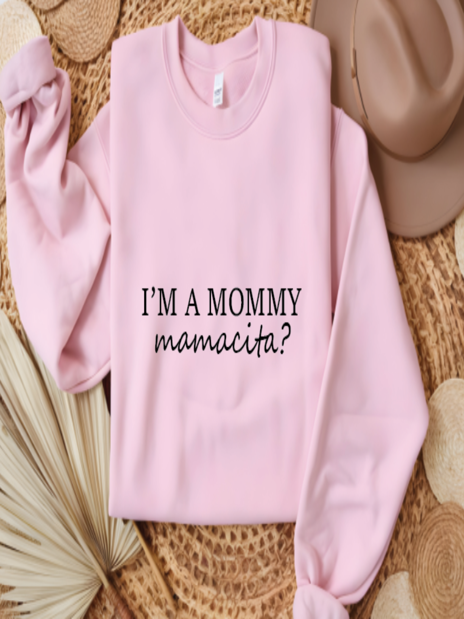 Pink sweatshirt with text 'I'm a mommy mamacita?' on a textured surface