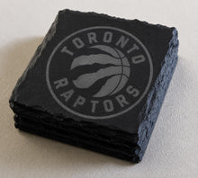 A set of four black slate coasters featuring the logo of the Toronto Raptors basketball team.