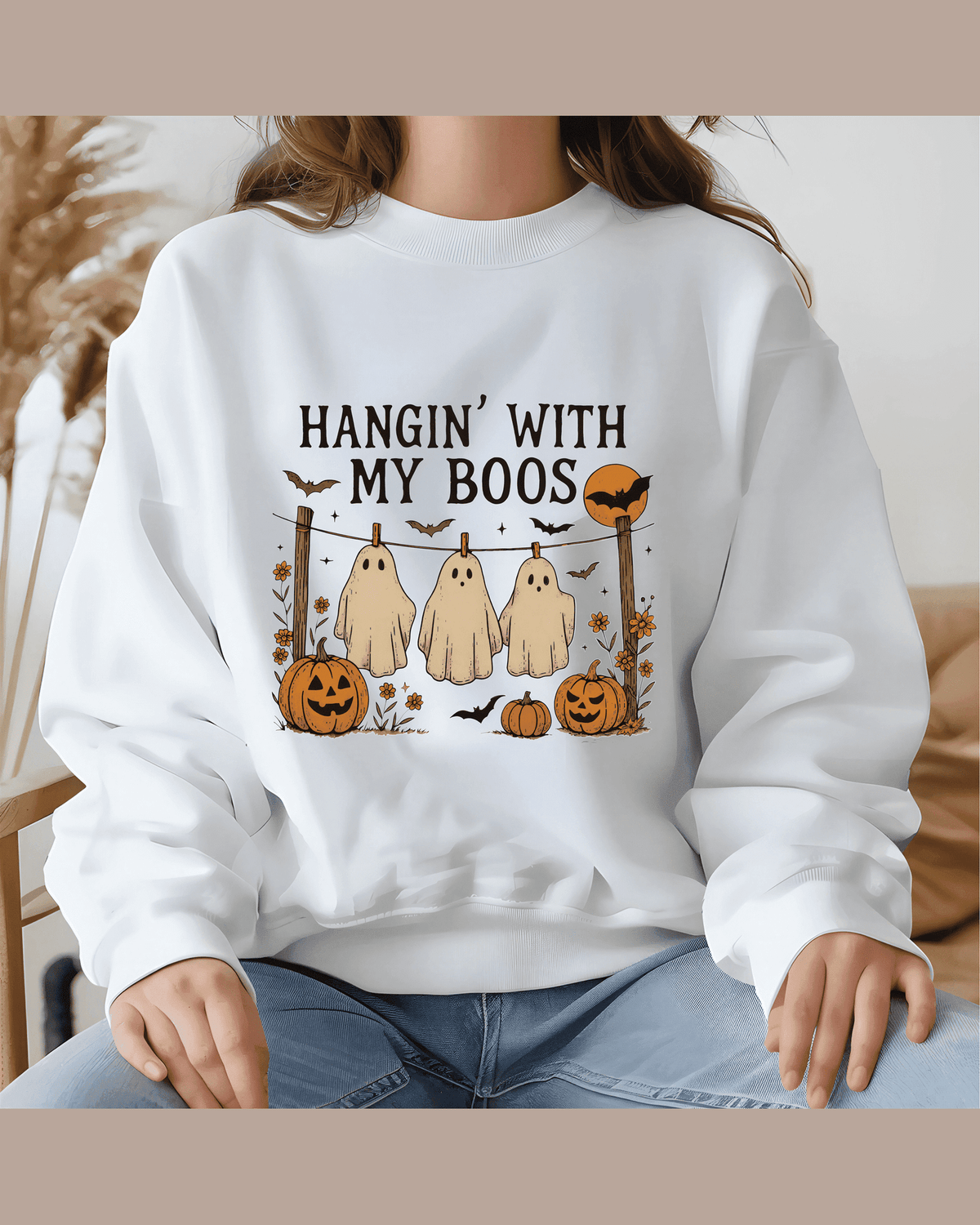 Person modeling white crewneck sweatshirt with 'Hangin With My Boos' Halloween graphic print