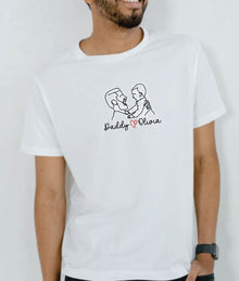 A man wearing a white t-shirt with a graphic design of two people, one of whom is a father and the other his daughter.