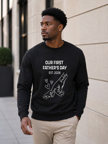 sweatshirt featuring personalized Our First Father’s Day design with minimalist daddy and baby hand outline artwork worn by male model outdoors.