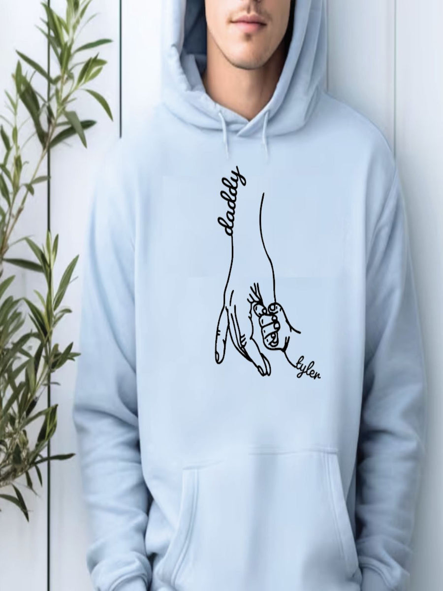 A person wearing a light blue hoodie with a graphic design depicting a hand holding a child's hand.