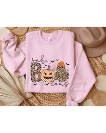 Pink crewneck sweatshirt with Fab Boo Lous Halloween graphic laid flat on woven surface