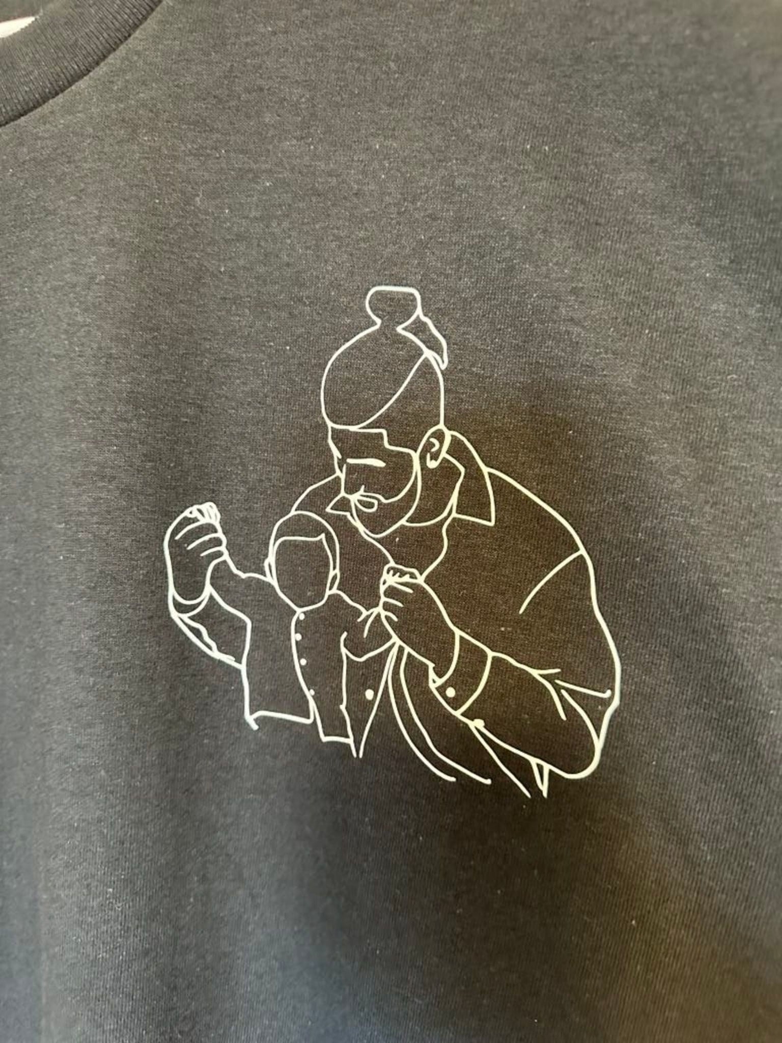 A black t-shirt with a white line drawing of a person holding a child.