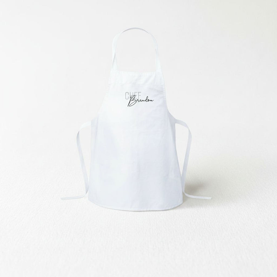 A white apron with the text "Chef Brandon" printed on it.