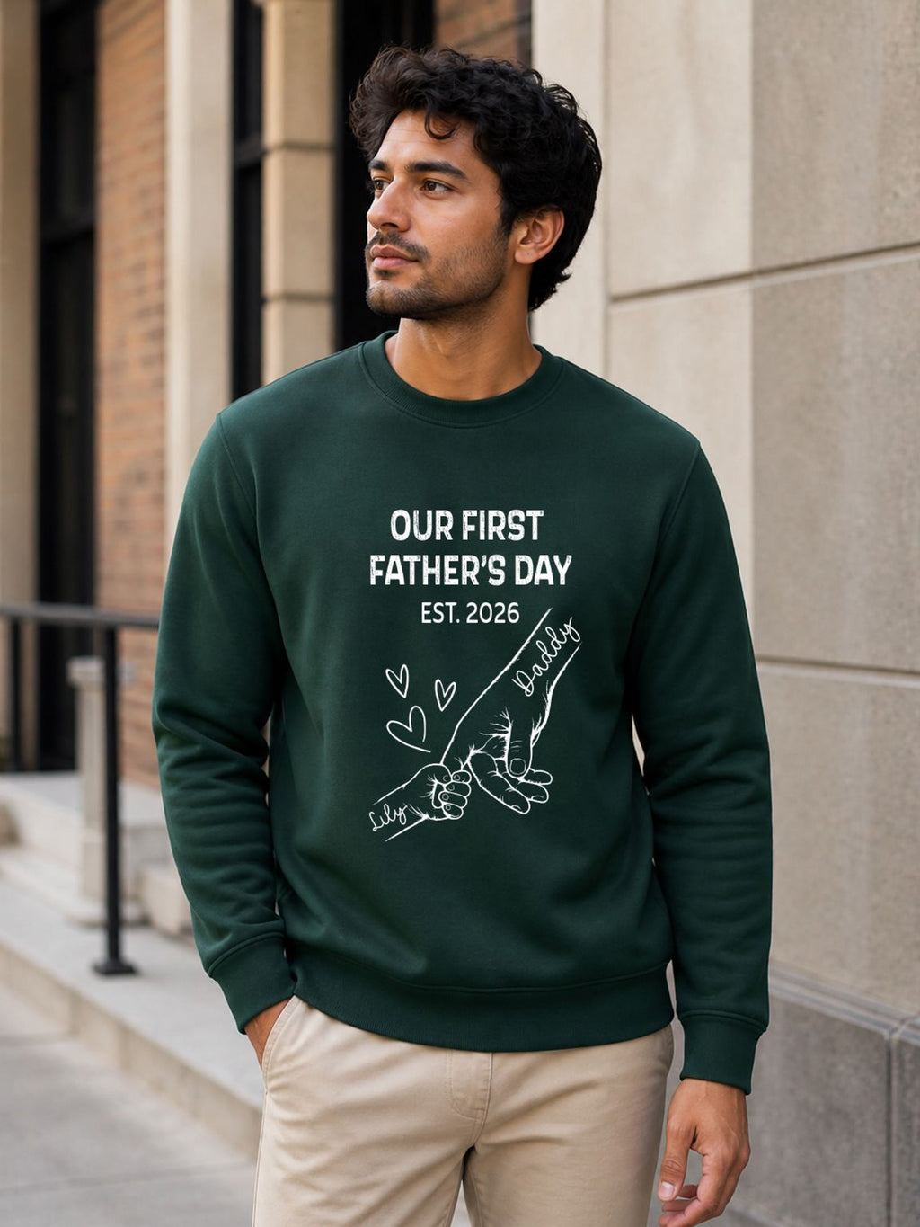 sweatshirt featuring personalized Our First Father’s Day design with minimalist daddy and baby hand outline artwork worn by male model outdoors.