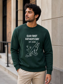 sweatshirt featuring personalized Our First Father’s Day design with minimalist daddy and baby hand outline artwork worn by male model outdoors.
