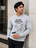 sweatshirt featuring personalized Our First Father’s Day design with minimalist daddy and baby hand outline artwork worn by male model outdoors.