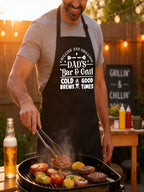 Dad’s Bar and Grill apron featuring funny BBQ typography design worn by man grilling outdoors in backyard.