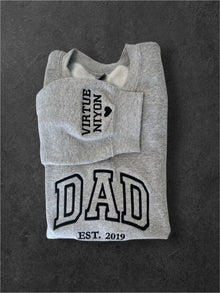 A gray sweatshirt with the text "VIRUTE N'YON" and "DAD" printed on it, along with the year "EST. 2019" below.