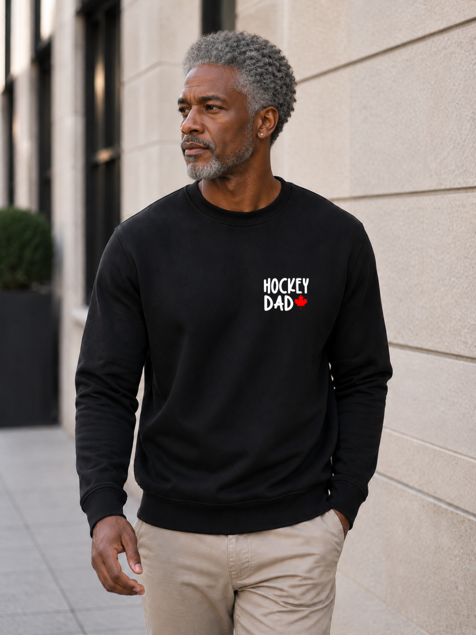 Hockey Dad crewneck sweatshirt featuring a minimalist white Hockey Dad design with a red Canadian maple leaf, modeled outdoors.