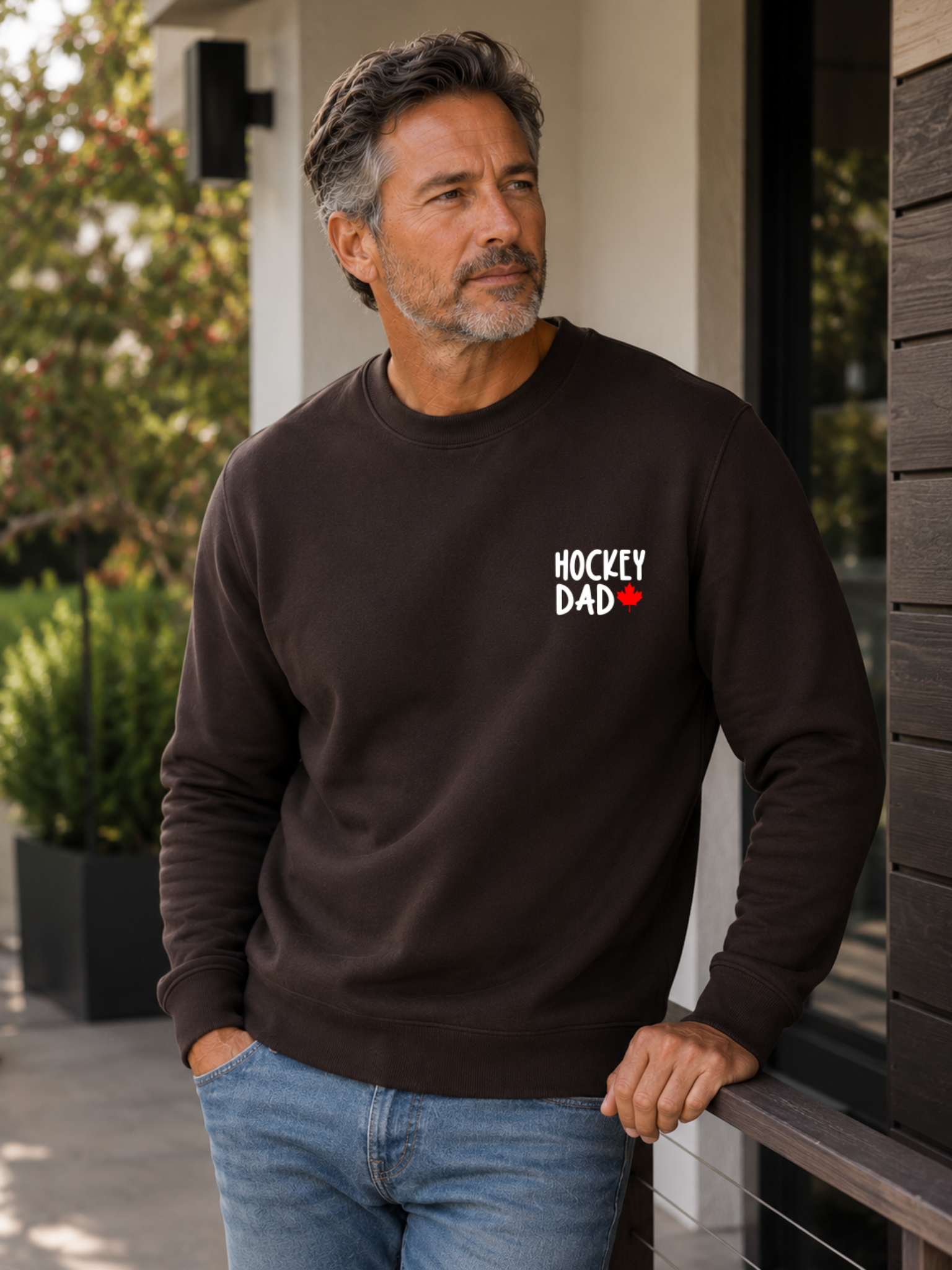 Hockey Dad crewneck sweatshirt featuring a minimalist white Hockey Dad design with a red Canadian maple leaf, modeled outdoors.
