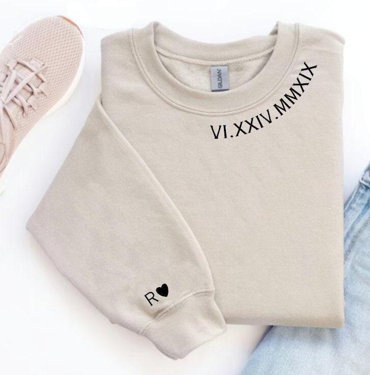 Beige sweatshirt with Roman numeral design and pink sneakers on a white background
