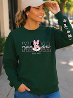 Woman wearing a green sweatshirt with 'Mama Mouse' design outdoors.