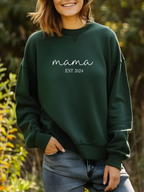 Person wearing a green sweatshirt with 'mama EST 2024' text, standing outdoors.