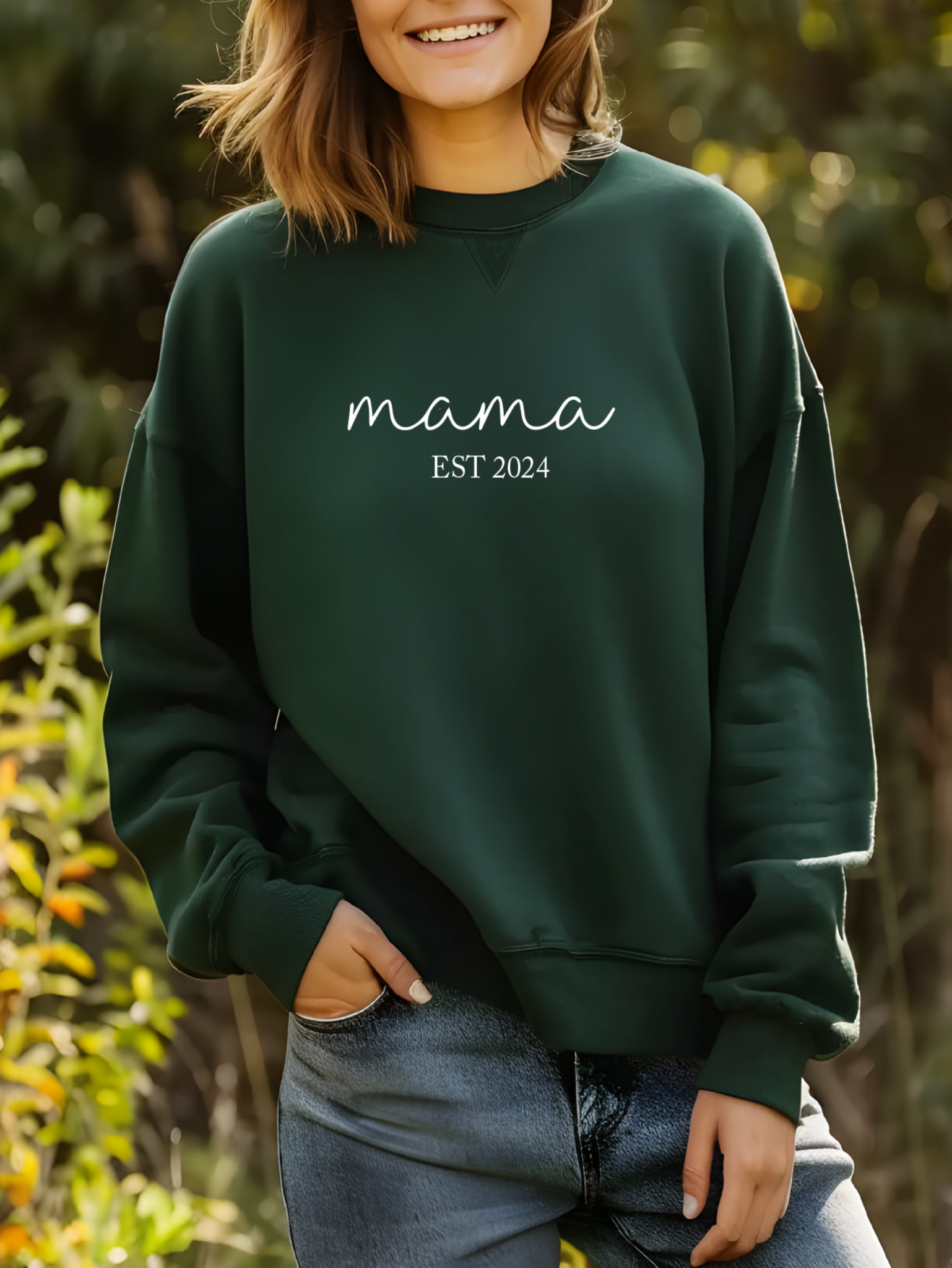 Person wearing a green sweatshirt with 'mama EST 2024' text, standing outdoors.