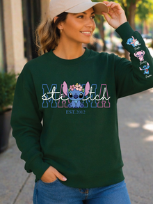 Woman wearing a green 'stitch' sweatshirt with character designs outdoors.